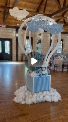 a blue and white wedding cake on top of a box in a room with wooden floors