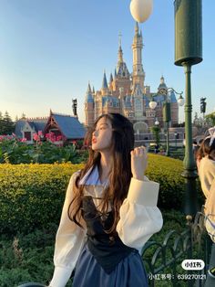 a woman standing next to a lamp post in front of a castle