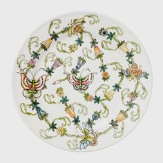 a white plate with colorful flowers and butterflies on it's rim, in the shape of a circle