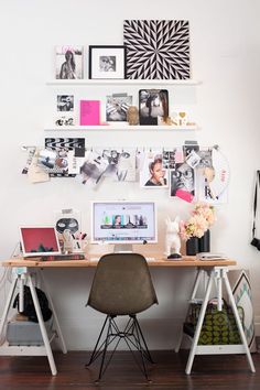 a desk with two chairs and pictures on the wall above it, along with a laptop computer