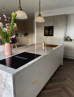 a modern kitchen with marble counter tops and gold trimming on the island, along with two hanging pendant lights