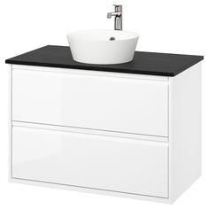 a white sink sitting on top of a counter next to a black and white cabinet