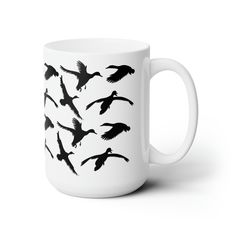 a white coffee mug with black birds flying in the sky on it's side