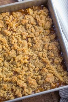 a casserole dish filled with meat and gravy on top of a wooden table