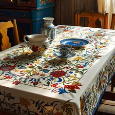 the table is covered with an elaborately designed cloth and has two cups on it