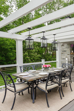 an outdoor dining table and chairs on a covered patio with white pergolan roof