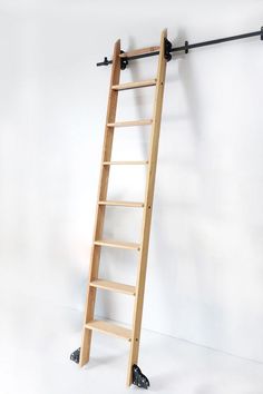 a wooden ladder leaning against a white wall with black metal bars on the top and bottom