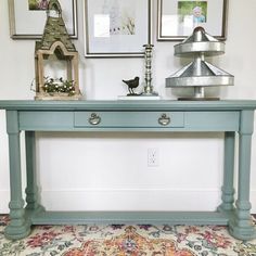 a blue table with pictures on the wall behind it and a birdhouse sitting on top