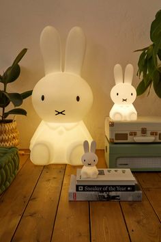 two bunny lamps sitting on top of a wooden table next to books and planters