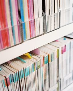 many books are stacked on top of each other in a bookcase with white shelves