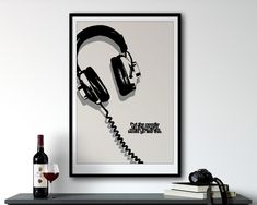 a poster with headphones and a bottle of wine on a table next to it