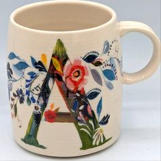 a coffee mug with flowers and leaves painted on the outside of it's handle