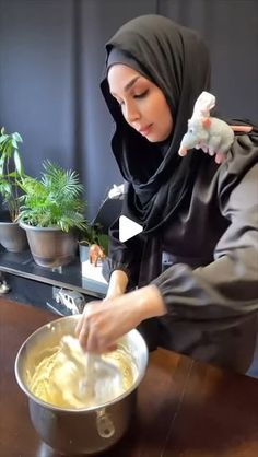 a woman in hijab mixing something in a bowl