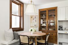 a dining room table with four chairs and a china cabinet in the corner behind it