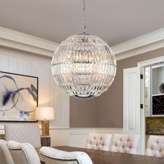 a chandelier hanging from the ceiling in a dining room with chairs and table