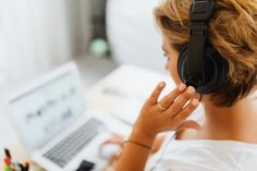 a woman with headphones on looking at her laptop