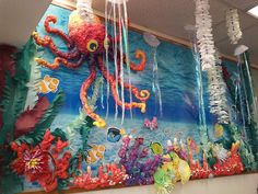 an octopus and other sea creatures are hanging from the ceiling in front of a mural