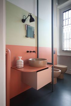 an instagram photo of a bathroom with orange and pink walls, a sink and toilet