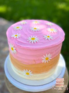 a pink and yellow cake with daisies on it