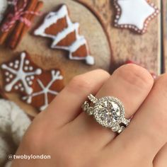 a close up of a person's hand with a ring on their finger and cookies in the background