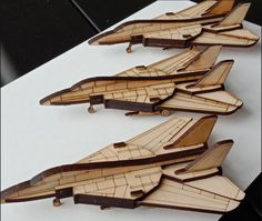 four wooden model airplanes sitting on top of a white table next to eachother