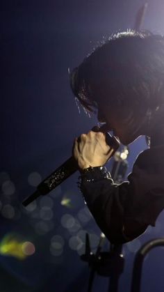 a man holding a microphone up to his ear while standing in front of a stage