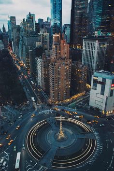 an aerial view of a city at night with lights and traffic on the streets in the foreground