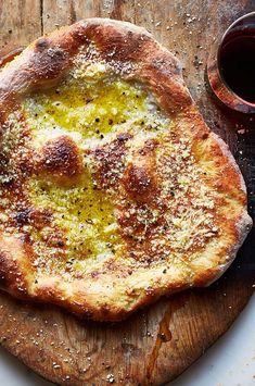 a pizza sitting on top of a wooden cutting board next to a cup of sauce