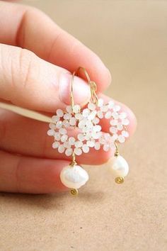 a hand holding a pair of earrings with pearls on it's ear ends and dangling from the end