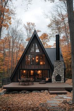 a large cabin style house in the woods with an outdoor deck and stone fireplace, surrounded by trees