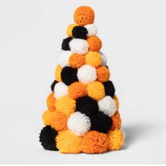 an orange, black and white christmas tree made out of pom - poms