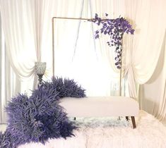 a white bench with purple flowers on it in front of a curtained room window