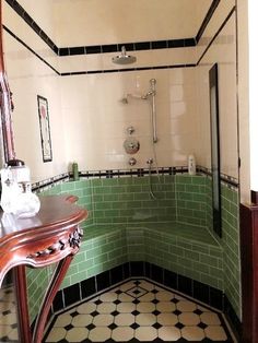 a bathroom with green and white tiles on the walls, flooring and shower stall