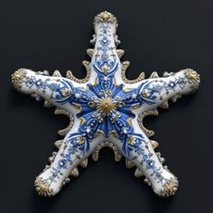 an ornate blue and white starfish ornament on a black background with gold accents