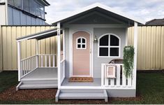 a small white house with a pink door and steps leading to the front porch area