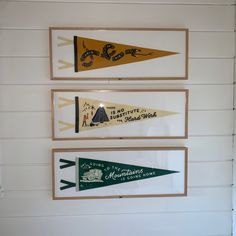 three pennants are hanging on the wall in front of a white painted room with wood paneling