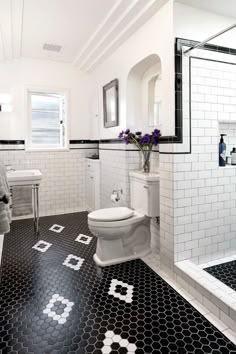 a bathroom with black and white tile flooring and walls, along with a walk in shower