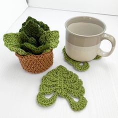 two crocheted coasters and a coffee cup on a white table with a green plant