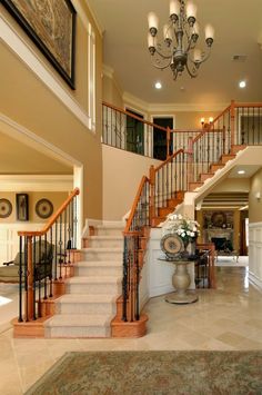 a large foyer with stairs, chandelier and rugs on the carpeted floor