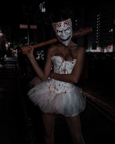 a woman dressed as a zombie holding a baseball bat and wearing a costume that says kiss me