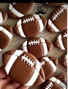 decorated cookies in the shape of footballs are being held by someone's hand