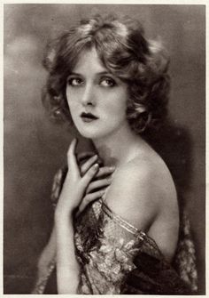 an old black and white photo of a woman with her hand on her chin, looking at the camera