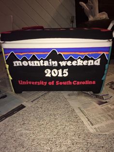 a cooler sitting on top of a table covered in papers and news paper with the words mountain weekend 2013