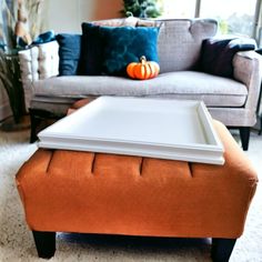 an orange ottoman sits in front of a gray couch