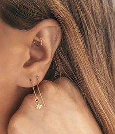 a close up of a person's ear wearing gold earrings with stars on them