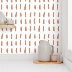 a white vase sitting on top of a counter next to a wall with brown spots