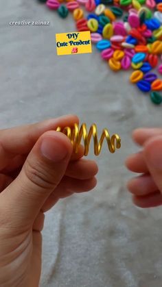 a person holding a small gold spiral ring in their left hand and colorful beads on the ground behind them