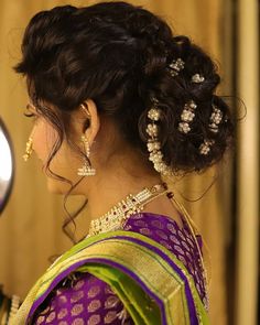 a woman in a purple and green saree looking into a mirror