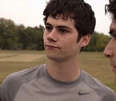 two young men standing next to each other on a field with trees in the background