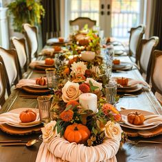 a table set for thanksgiving dinner with pumpkins and flowers